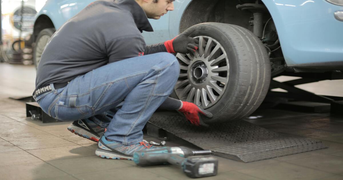 A man removing a tyre to find the MacPherson strut.