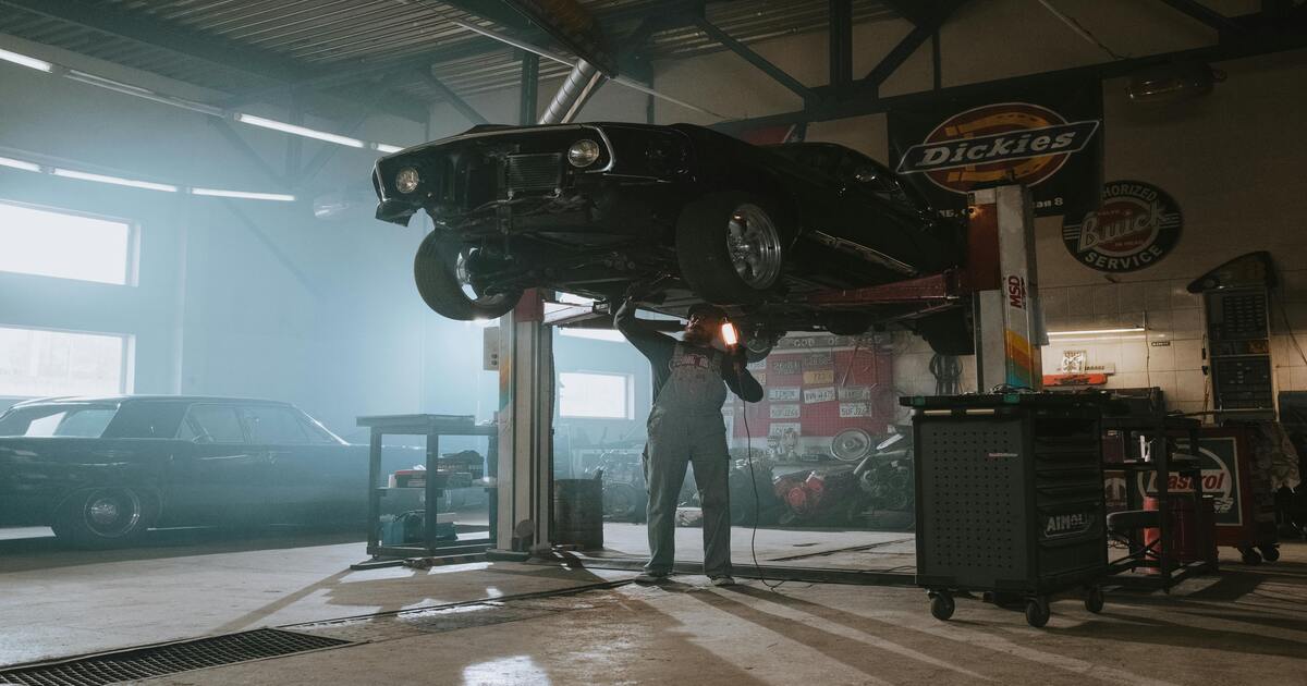 A man at a mechanic checking if he can upgrade his car with double wishbone suspension.