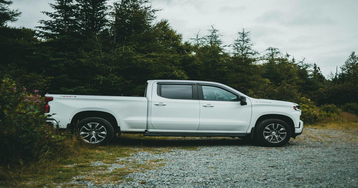 A white Silverado 1500 upgraded for better ground clearance parked next to a road.